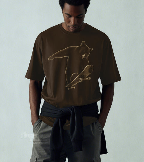 Model wearing a brown t-shirt printed in tonal cream with a bear riding a skateboard.