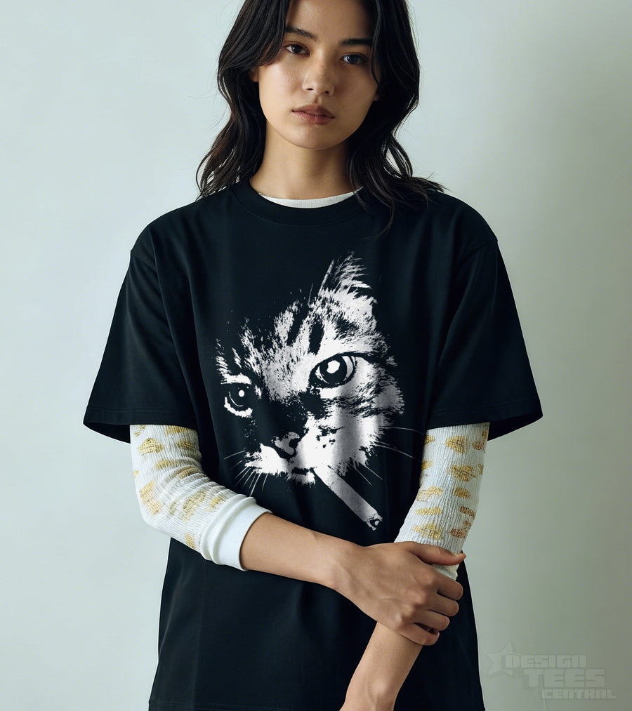 Black t-shirt worn by a model, printed with a large white portrait of a tabby cat holding a lit cigarette in its mouth.