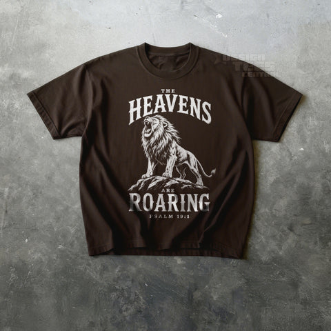 Brown t-shirt printed in cream with a roaring lion on rocks and the text The Heavens Are Roaring, Psalm 19:1.